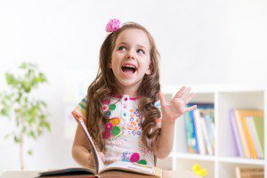 cute smiling child girl reading book at home